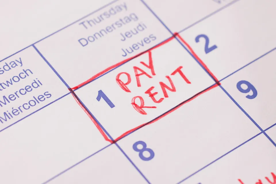 Close-up of 'Pay rent' note in red marker on day 1 of monthly calendar.